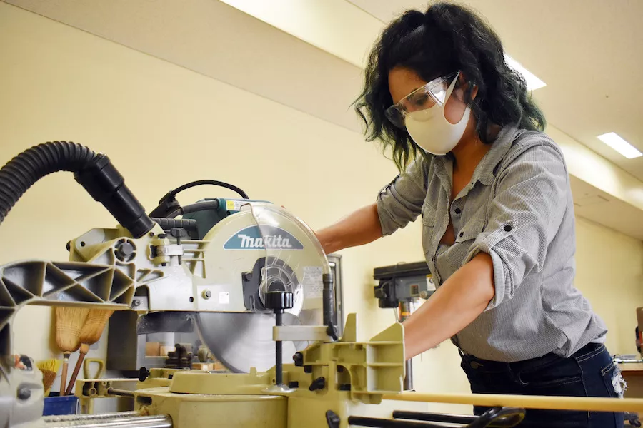 A woman at army camp doing woodworking.